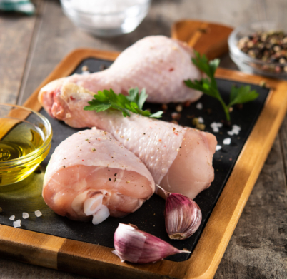 Raw chicken meat legs with spices, herbs and olive oil on wooden table
